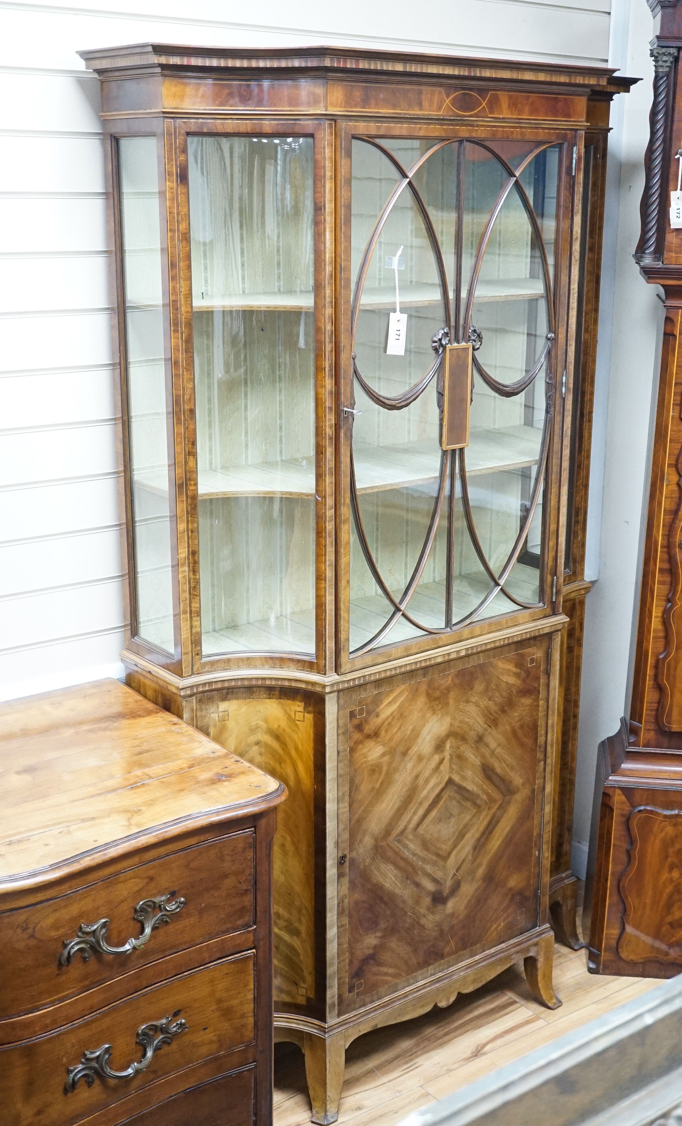 A Sheraton Revival mahogany display cabinet, crossbanded and inlaid, shape fronted, single glazed door on splay bracket feet, width 113cm, depth 36cm, height 198cm